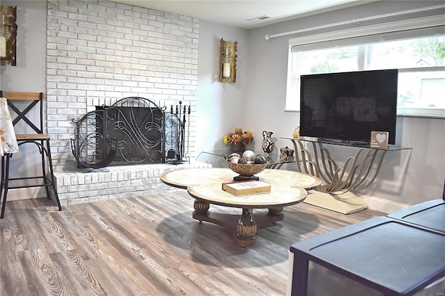 living room with a brick fireplace and hardwood / wood-style flooring