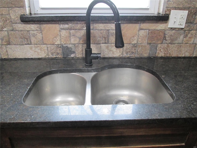 room details featuring white cabinetry, sink, and dark stone counters