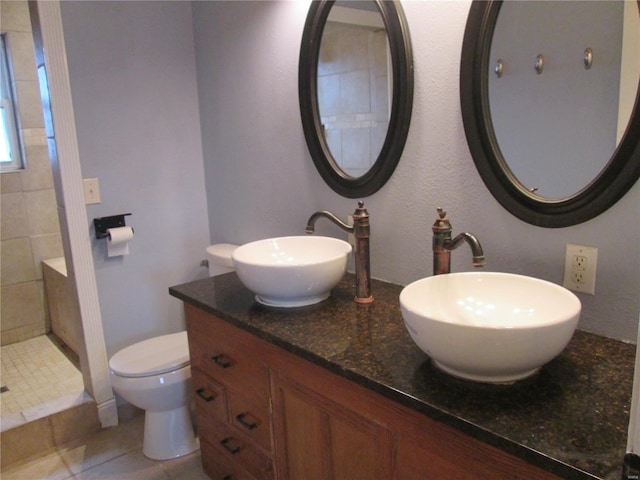 bathroom featuring a tile shower, vanity, tile patterned flooring, and toilet