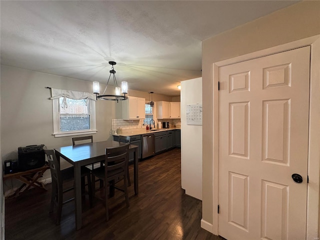 dining area with sink, a notable chandelier, and dark wood-type flooring