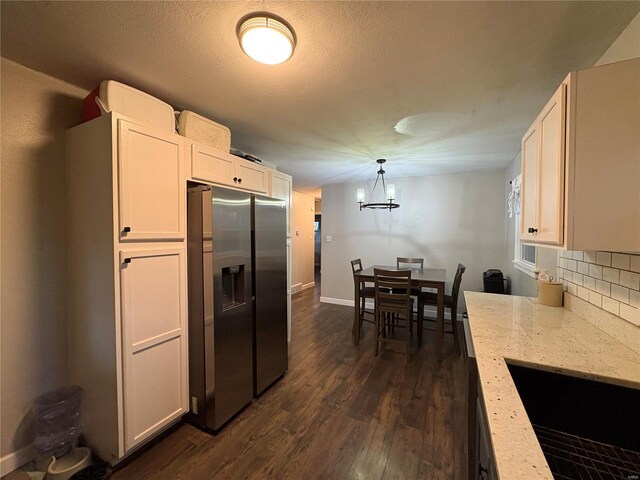 kitchen featuring stainless steel refrigerator with ice dispenser, dark hardwood / wood-style floors, pendant lighting, decorative backsplash, and white cabinets