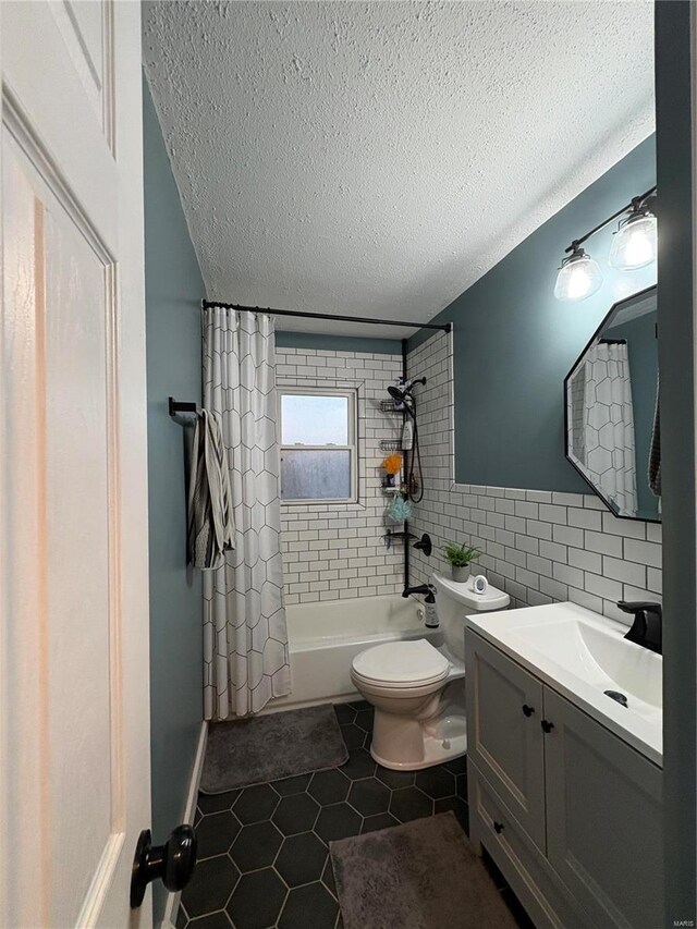 full bathroom with shower / tub combo with curtain, tile walls, toilet, tile patterned floors, and a textured ceiling