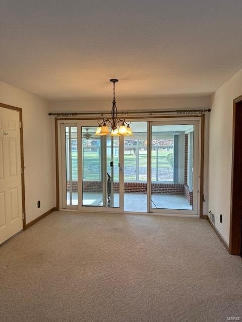 empty room featuring an inviting chandelier, carpet, and a wealth of natural light