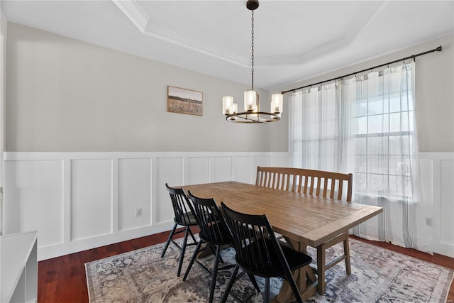 dining area featuring dark hardwood / wood-style flooring, a tray ceiling, ornamental molding, and an inviting chandelier