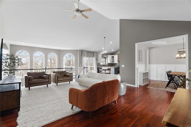 living room featuring dark hardwood / wood-style flooring, ceiling fan with notable chandelier, and high vaulted ceiling