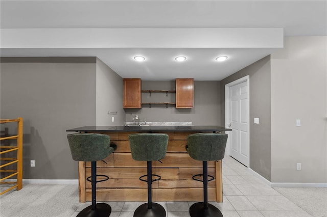 kitchen featuring light tile patterned floors, a kitchen breakfast bar, and kitchen peninsula