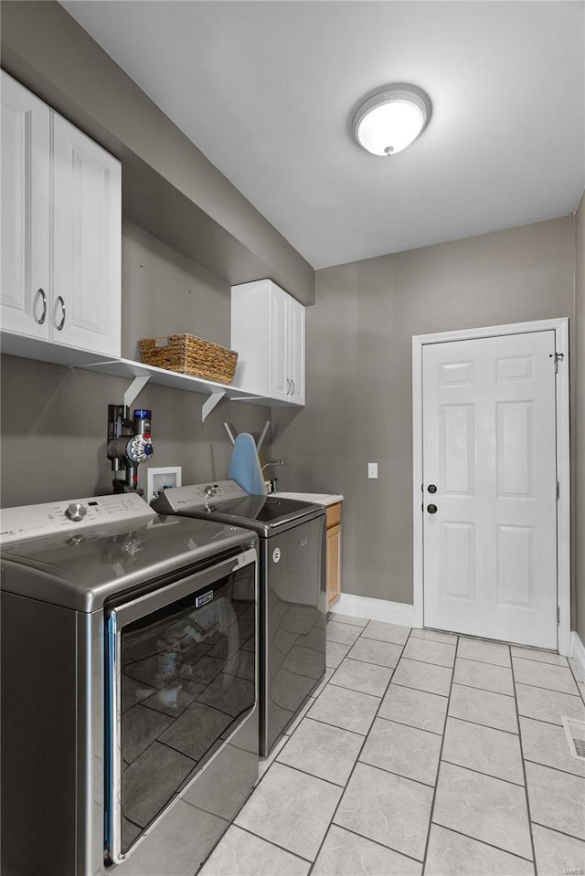 washroom featuring cabinets, sink, washer and dryer, and light tile patterned floors