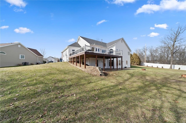 rear view of house featuring cooling unit, a wooden deck, and a lawn