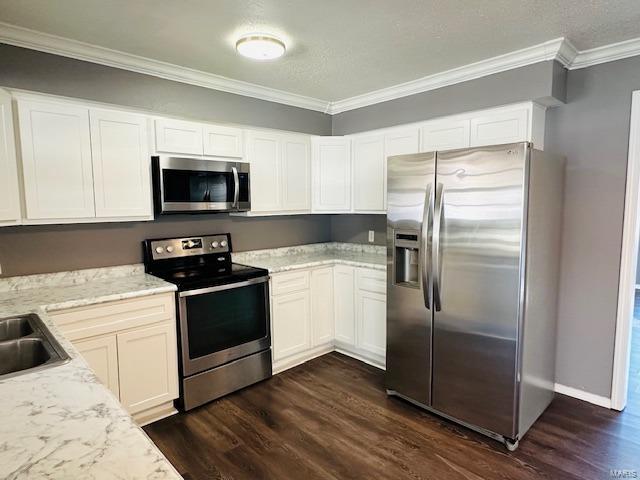 kitchen featuring stainless steel appliances, white cabinetry, dark hardwood / wood-style floors, and crown molding