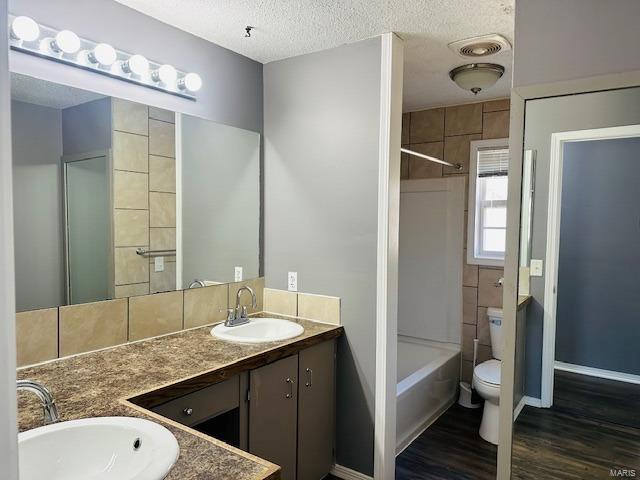 full bathroom featuring vanity, toilet, hardwood / wood-style floors, and a textured ceiling