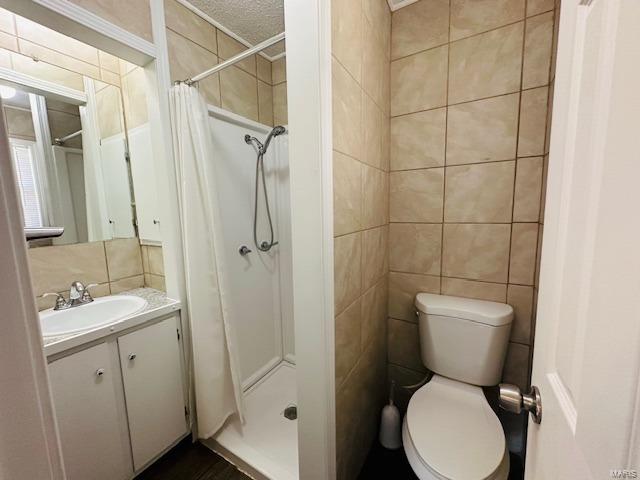 bathroom featuring tile walls, vanity, toilet, and a shower with shower curtain