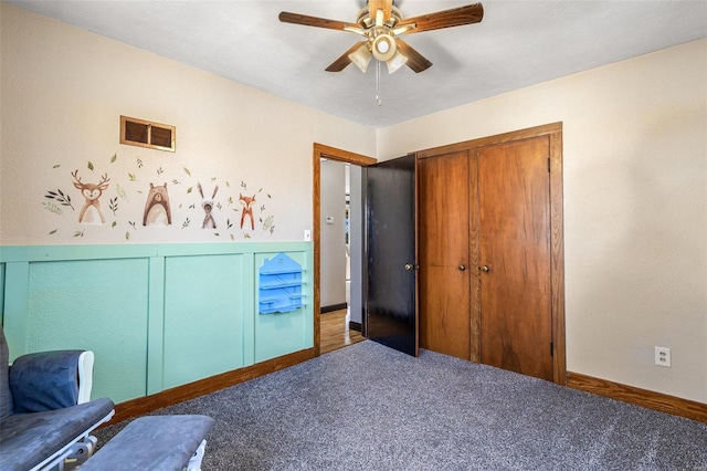 unfurnished bedroom with ceiling fan, dark carpet, and a closet