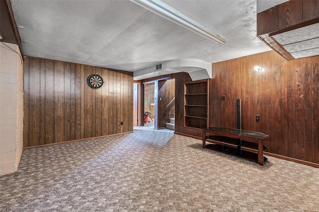 interior space with wood walls, a textured ceiling, and carpet flooring