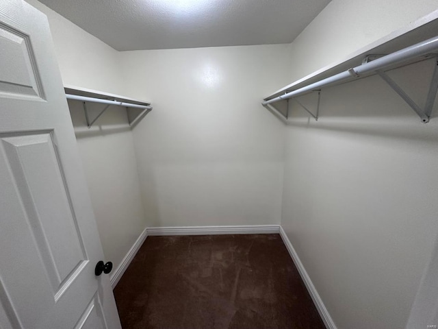 spacious closet featuring dark carpet