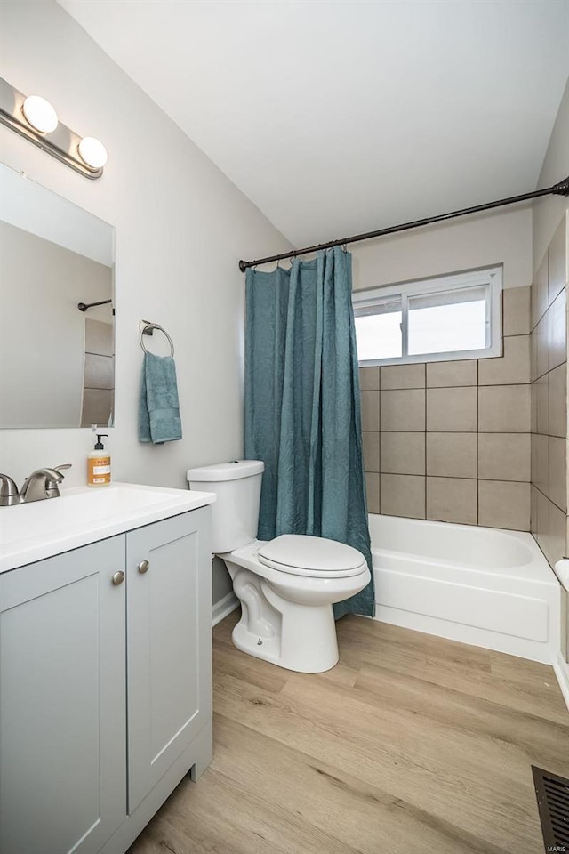 full bathroom with hardwood / wood-style flooring, vanity, shower / tub combo with curtain, and toilet