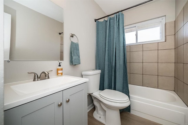 full bathroom with hardwood / wood-style flooring, vanity, shower / tub combo with curtain, and toilet