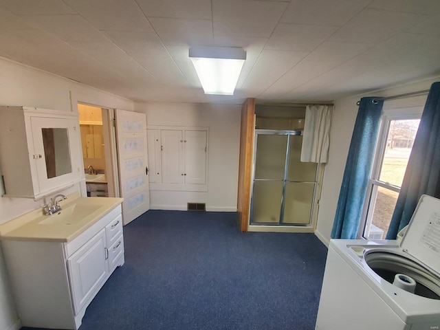 bathroom with sink, washer / dryer, and a shower with shower door