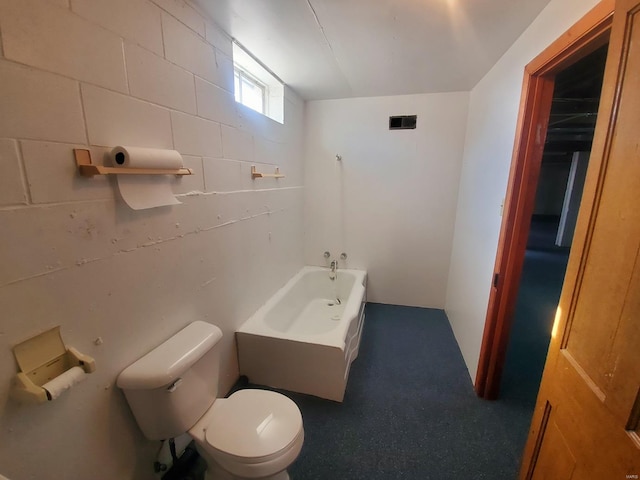 bathroom with a tub to relax in and toilet