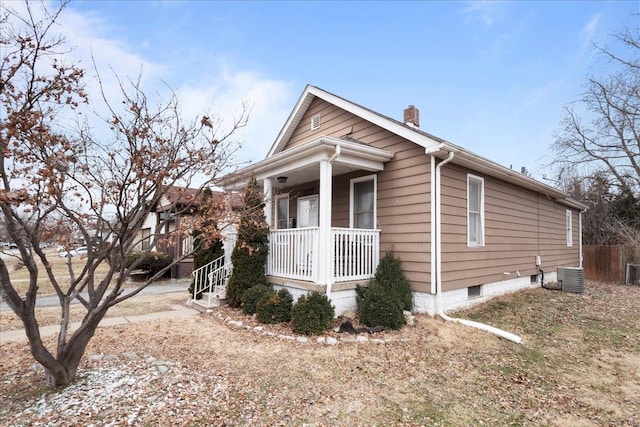 view of front of house featuring a porch, a chimney, and central AC unit