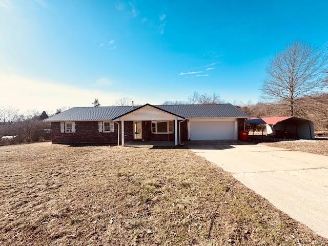 ranch-style home with a garage, a carport, and a front yard