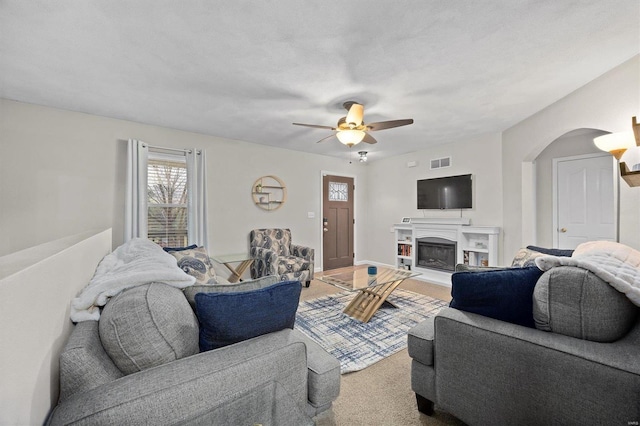 living room featuring ceiling fan, carpet flooring, and a textured ceiling