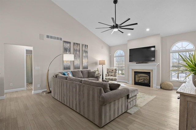 living room featuring ceiling fan, a healthy amount of sunlight, high vaulted ceiling, and light hardwood / wood-style flooring