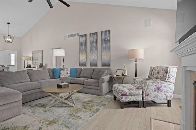 living room with hardwood / wood-style flooring, ceiling fan with notable chandelier, and high vaulted ceiling