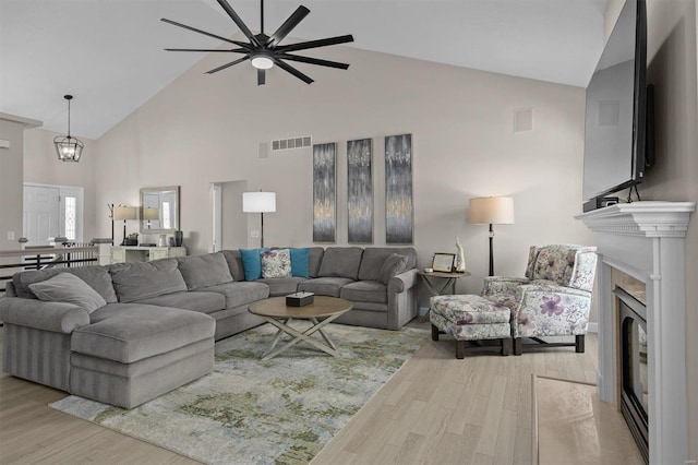 living room with ceiling fan, high vaulted ceiling, and light wood-type flooring