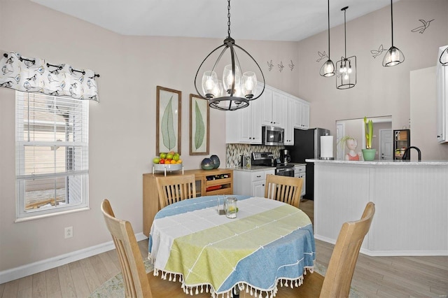 dining area featuring a chandelier, a high ceiling, and light wood-type flooring