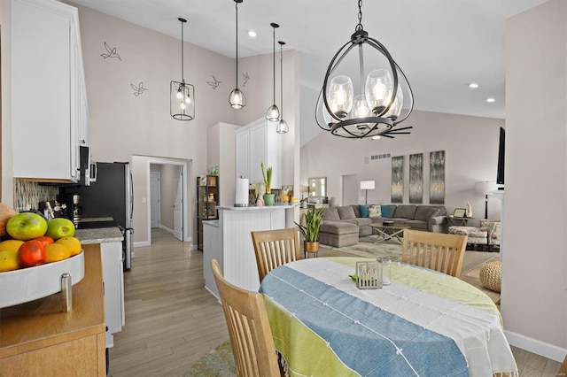 dining room featuring an inviting chandelier, light hardwood / wood-style flooring, and a high ceiling