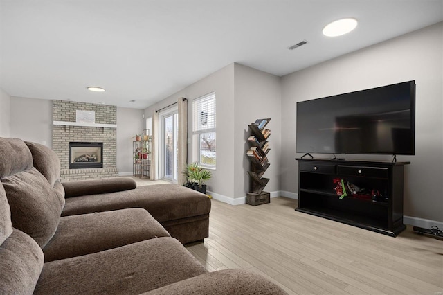 living room featuring light hardwood / wood-style floors and a brick fireplace