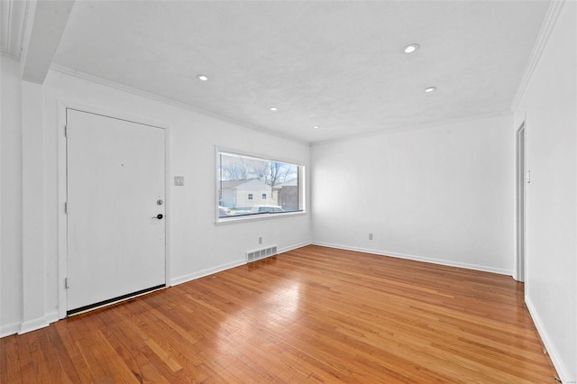 foyer entrance with ornamental molding and light hardwood / wood-style floors