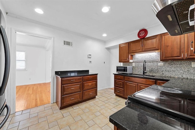 kitchen with sink, stainless steel appliances, tasteful backsplash, ornamental molding, and dark stone counters