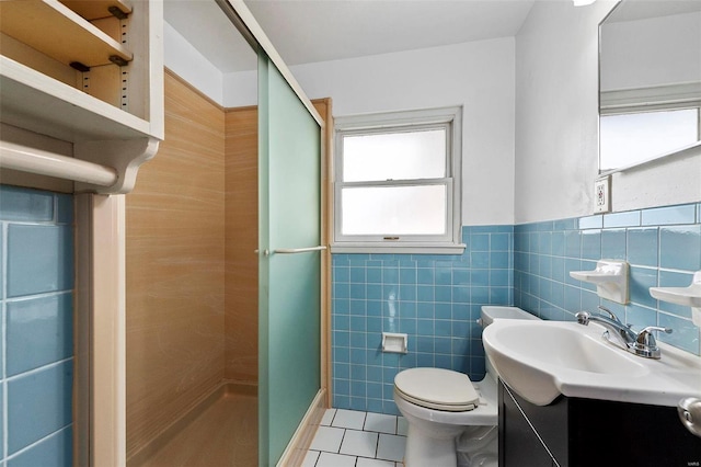 bathroom with tile patterned flooring, a shower with door, tile walls, and toilet