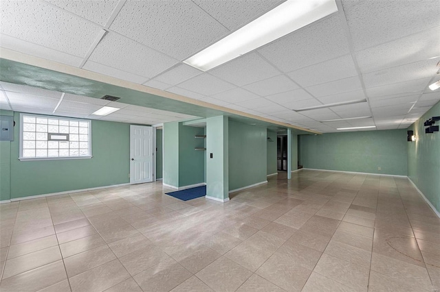 basement featuring a paneled ceiling and electric panel