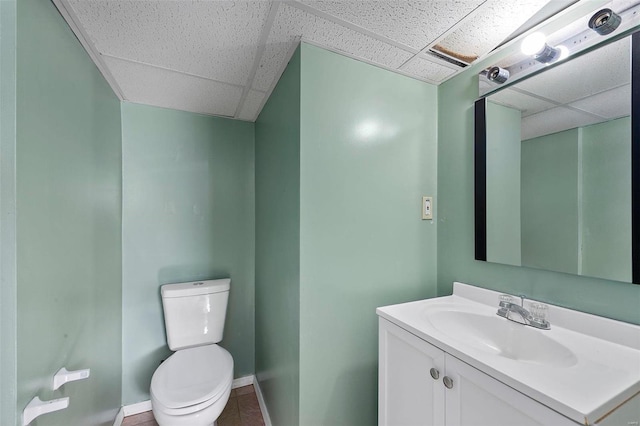 bathroom featuring vanity, toilet, and a drop ceiling