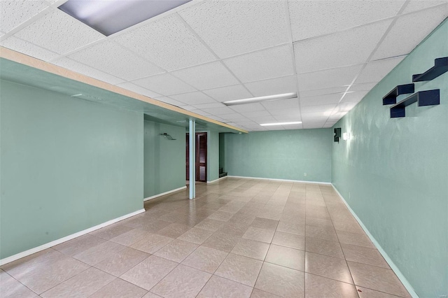 basement with tile patterned flooring and a paneled ceiling