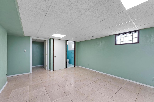 basement with light tile patterned floors and a drop ceiling