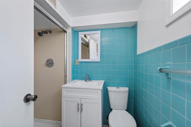 bathroom with vanity, toilet, and tile walls