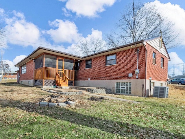 rear view of property with a yard, central AC unit, and a sunroom