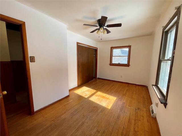 unfurnished bedroom featuring a closet, light wood-type flooring, a ceiling fan, and baseboards