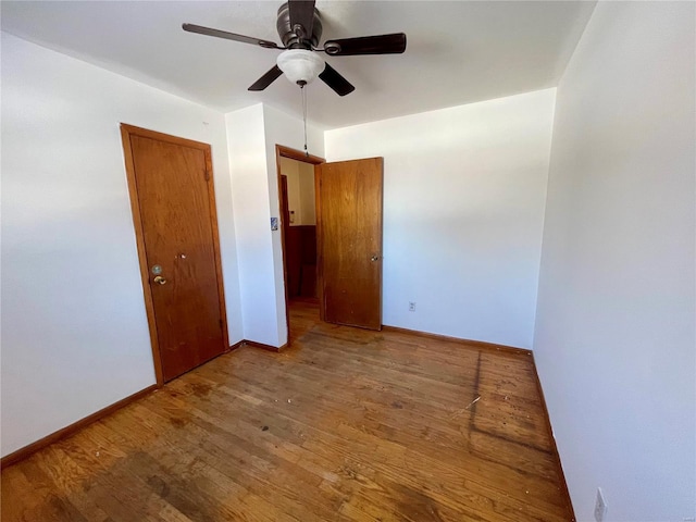 empty room with a ceiling fan, baseboards, and wood finished floors