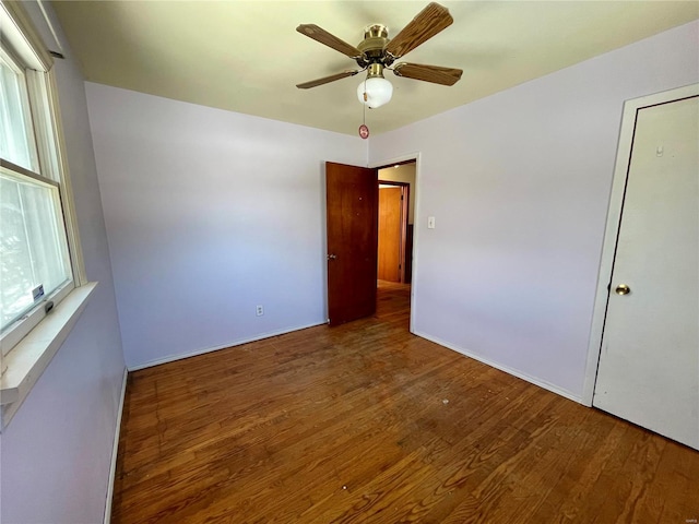 empty room with a ceiling fan and dark wood finished floors