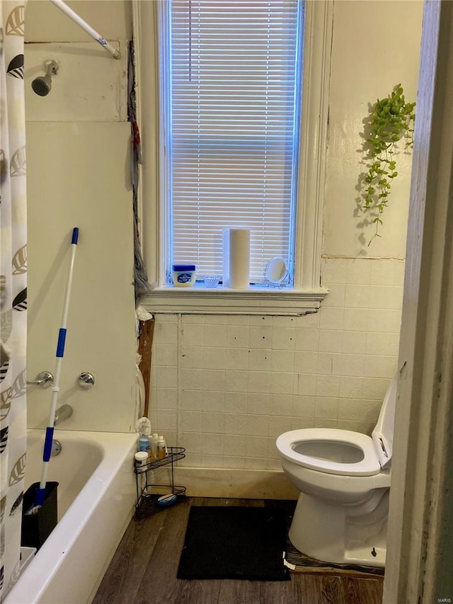 bathroom with wood-type flooring, toilet, shower / tub combo, and tile walls