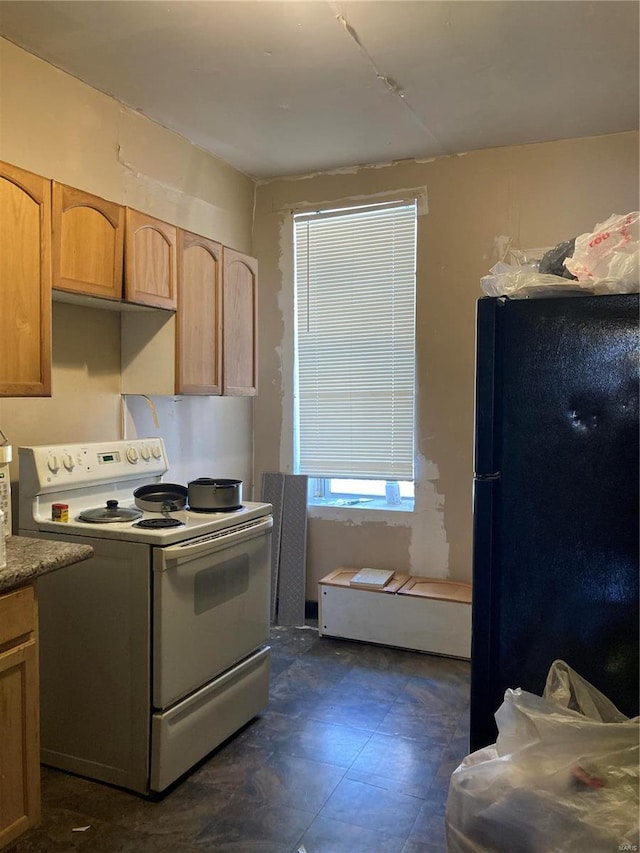 kitchen with light brown cabinetry, electric range, and black fridge