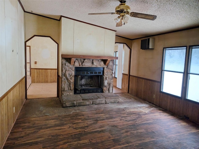 unfurnished living room with dark hardwood / wood-style floors, a fireplace, wooden walls, and a textured ceiling