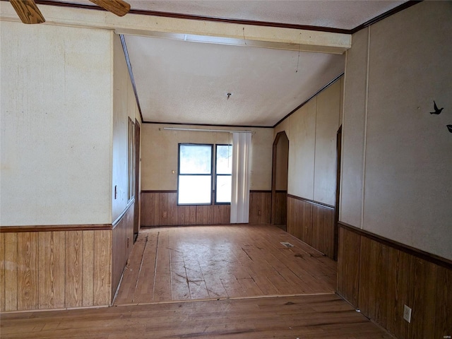 spare room featuring crown molding, wooden walls, and light hardwood / wood-style floors