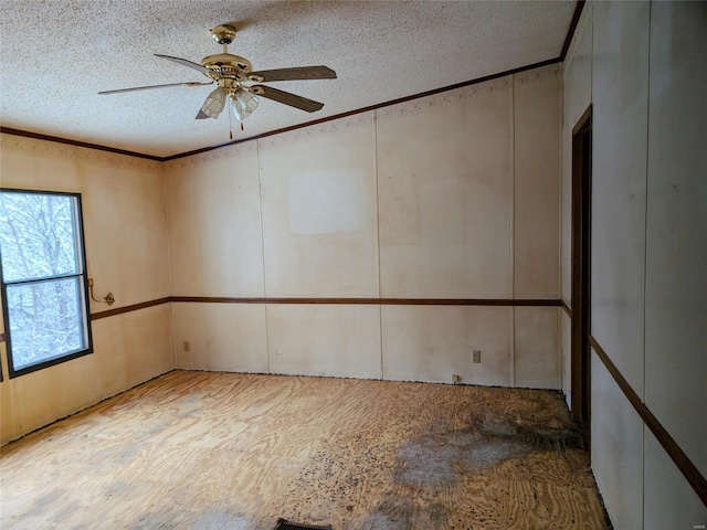 empty room featuring ceiling fan, ornamental molding, and a textured ceiling