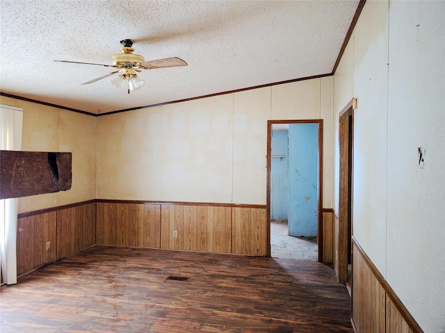 empty room with crown molding, dark wood-type flooring, and a textured ceiling