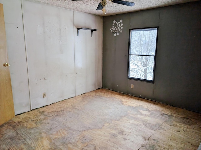 unfurnished room with ceiling fan and a textured ceiling